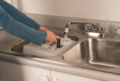 Person filling BISSELL® Big Green® Tank with water from sink